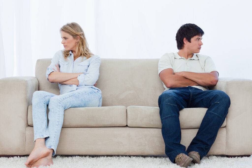 Angry couple sitting on couch looking away from eachother