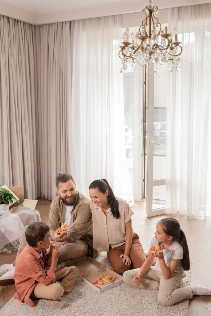 Family sitting on the living room floor, sharing pizza together