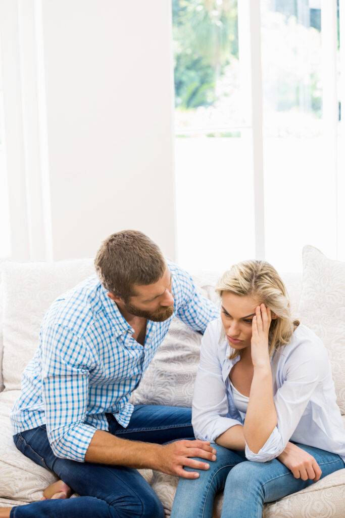 Man comforting his partner on the couch in their living room
