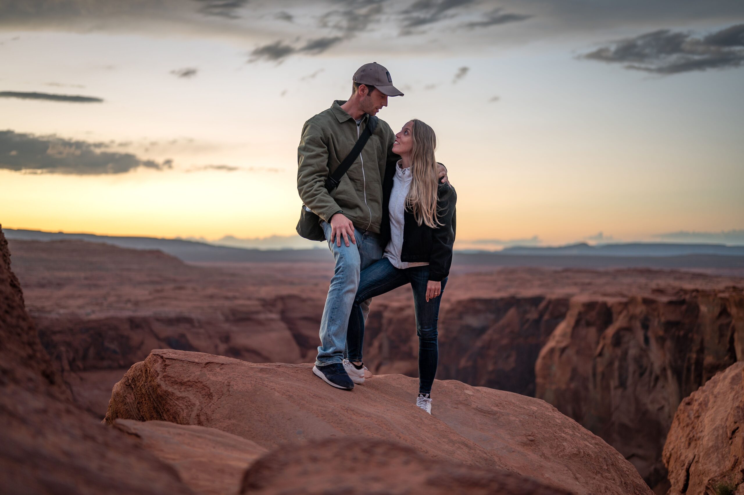 Couple embracing on a desert rock outcrop at sunset